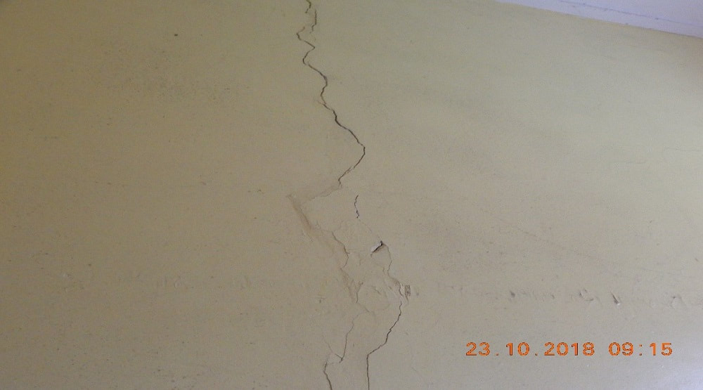 An internal biege wall with a vertical crack